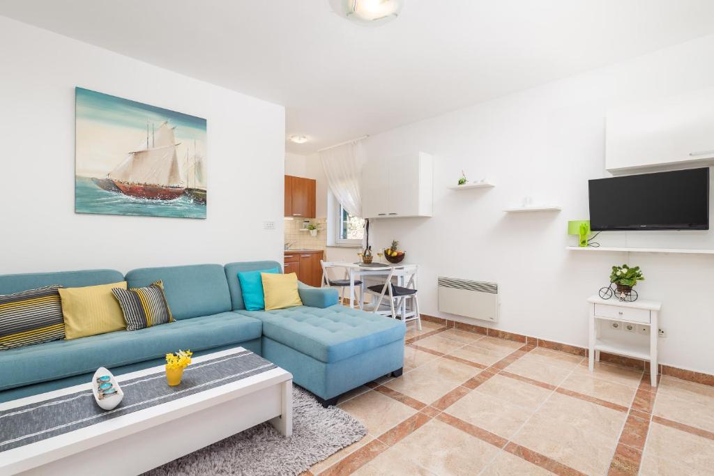 een woonkamer met een blauwe bank en een keuken bij Blue Dream Studio Apartment with a pool in Opatija