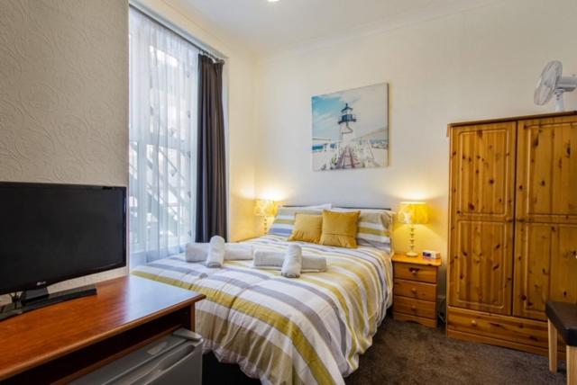 um quarto com uma cama grande e uma televisão em Capri Guesthouse em Llandudno