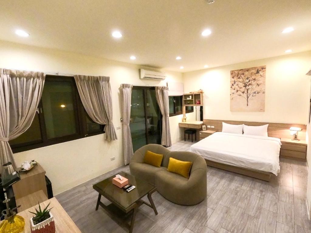 馬公市にある澎湖夏日南風民宿のベッド、ソファ、テーブルが備わるホテルルームです。