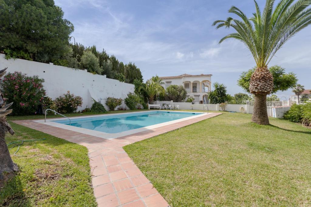 una piscina en un patio con una palmera en Mi Casa, en Caleta de Vélez