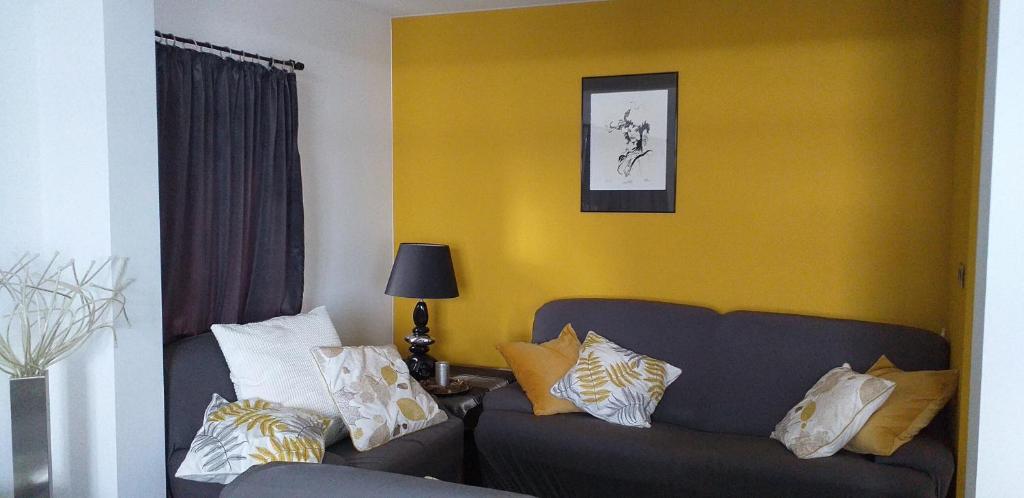 chez Chantal - appartement privatif في Yvoir: غرفة معيشة مع أريكة وجدار أصفر