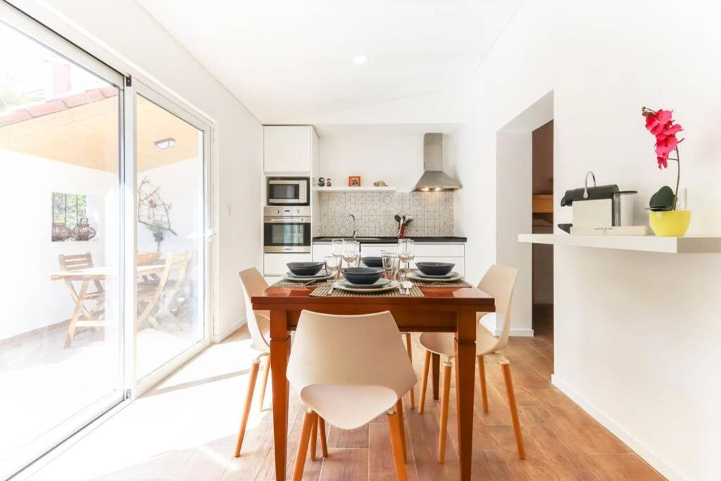 cocina y comedor con mesa de madera y sillas en CAPARICA BEACH VILLA, en Trafaria