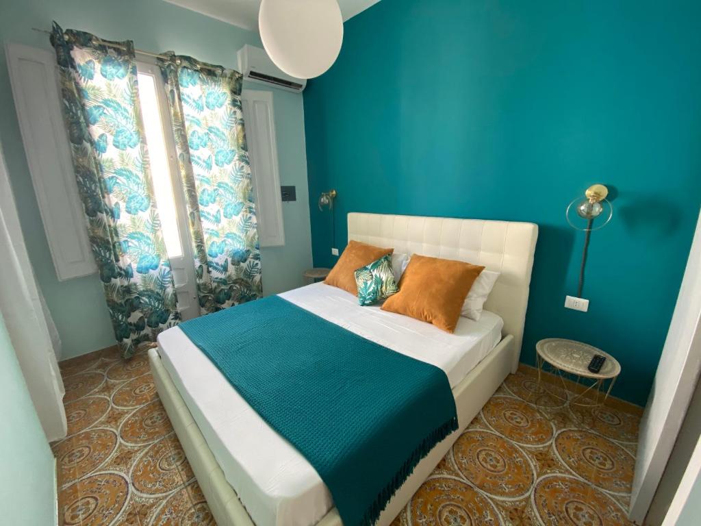 ein blaues Schlafzimmer mit einem Bett mit orangefarbenen Kissen in der Unterkunft AFFITTACAMERE PIAZZA MAMELI in Torre Lapillo