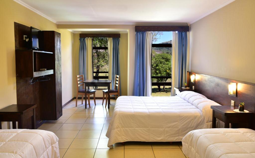 a hotel room with two beds and a table at Hotel El Paraiso De La Sierra in Tandil