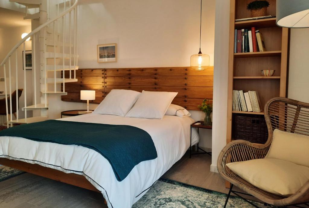 een slaapkamer met een bed en een stoel en een boekenplank bij Casa Carmen in Laroles