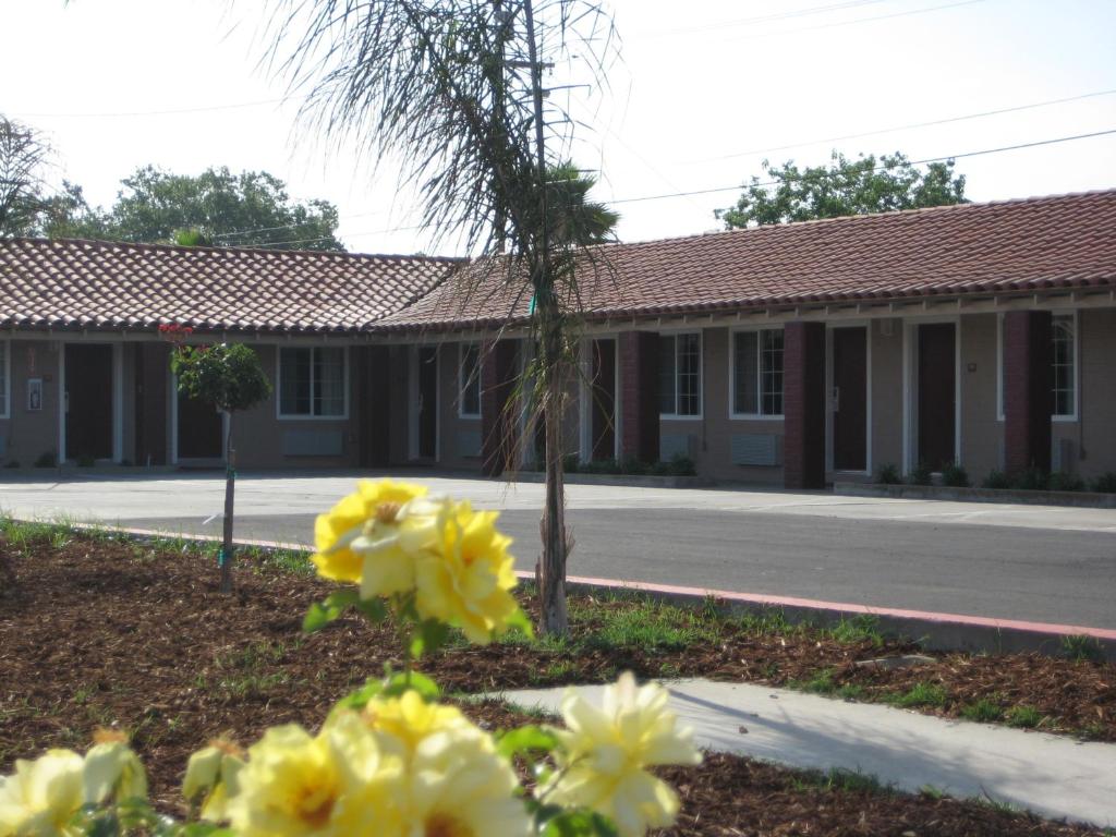 a building with yellow flowers in front of a street at Americas Best Value Inn - Porterville in Porterville