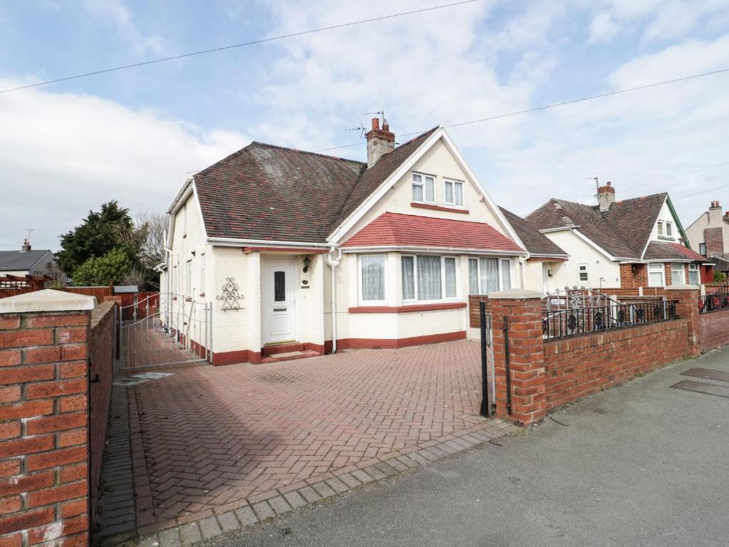 a white house with a brick fence in front of it at Dunromin in Llandudno