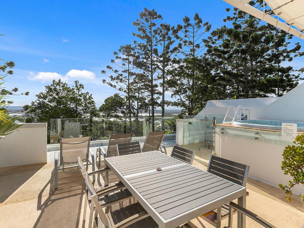 Una mesa y sillas en un patio con vista al mar. en Picture Point Penthouse 11 - Private Rooftop Spa, en Noosa Heads