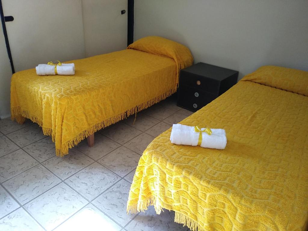 2 camas con sábanas amarillas y toallas blancas. en Al lado en Córdoba