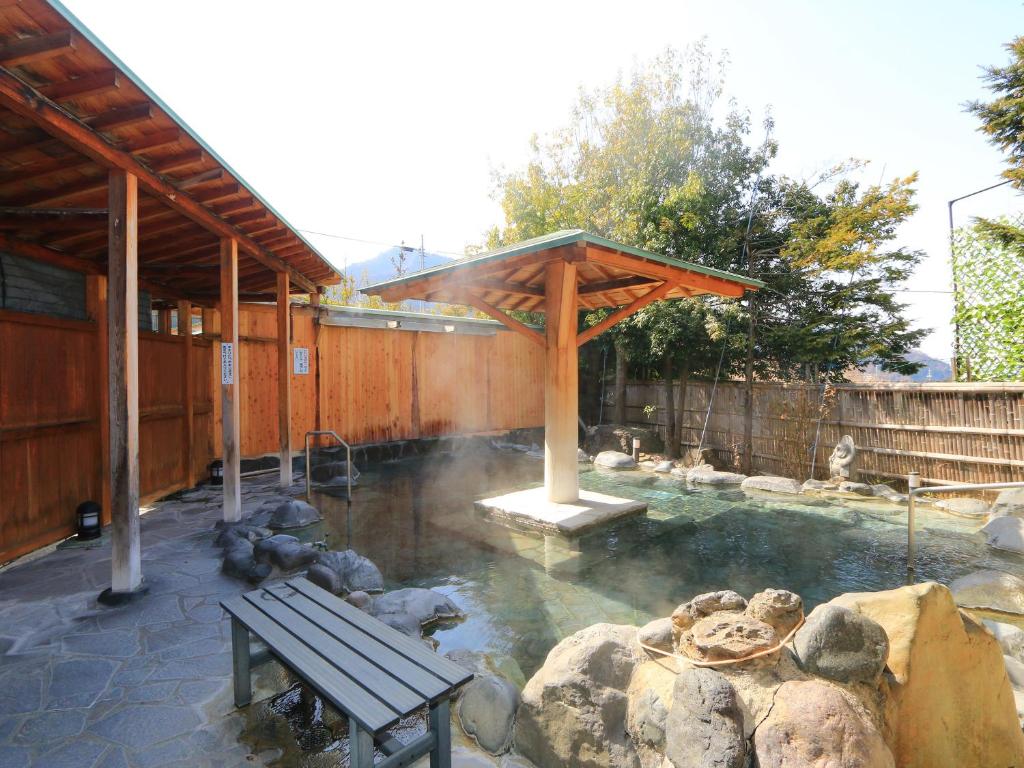 a pool of water with a bench and a pavilion at Minshuku Miyama in Yamanouchi