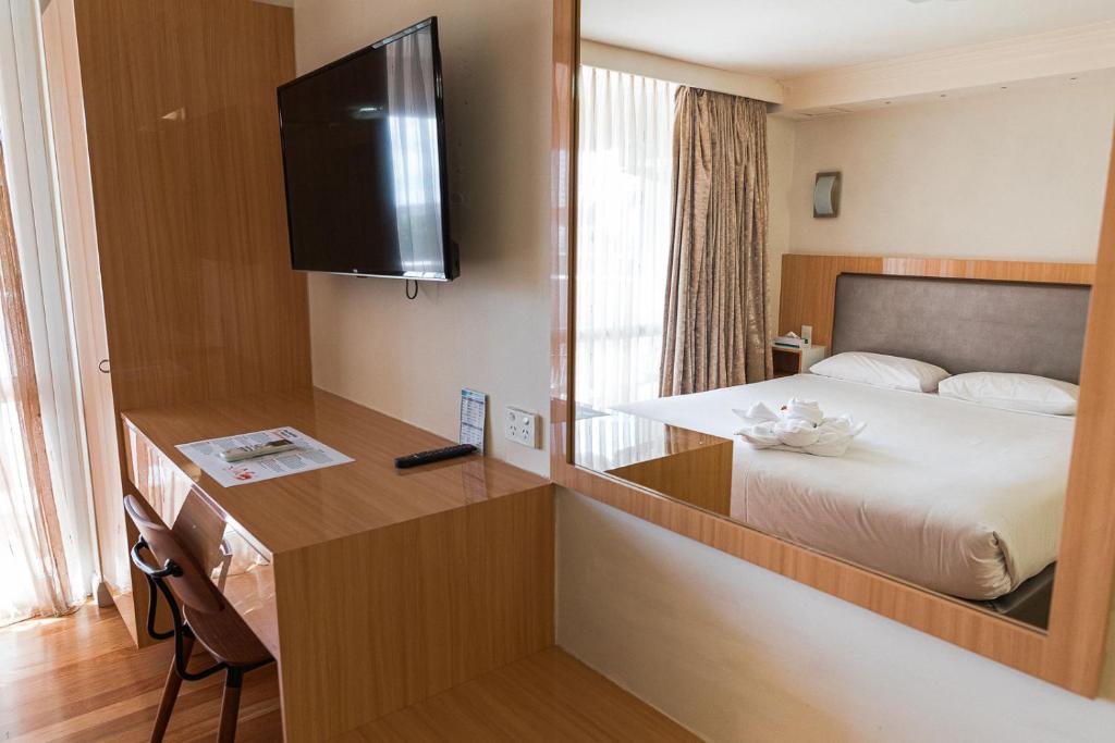 a hotel room with a bed and a desk with a mirror at Indian Ocean Hotel in Perth