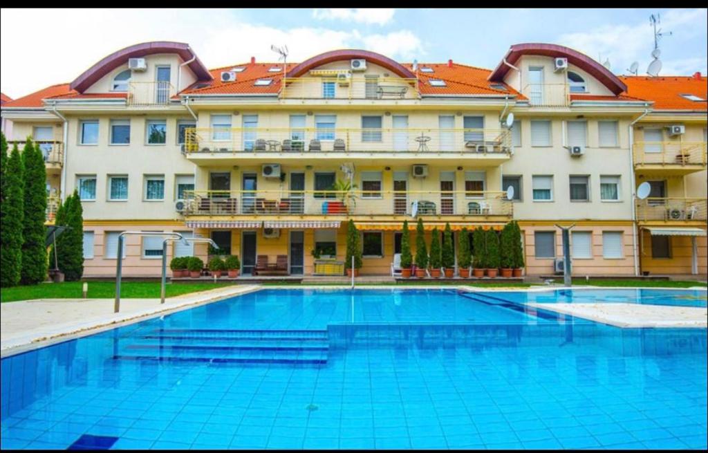 a swimming pool in front of a large building at Hajdúszoboszló Toscana Panoráma in Hajdúszoboszló