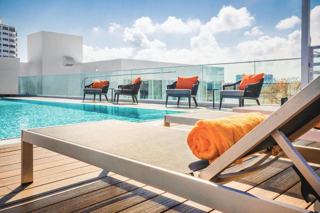 a pool on the roof of a building with chairs at Berkeley Park MGallery Hotel Collection in Miami Beach
