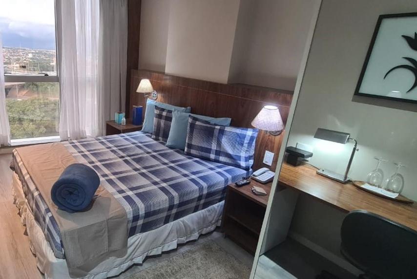 a bedroom with a bed with blue pillows and a window at Apto aconchegante no Centro de Taguatinga. in Taguatinga