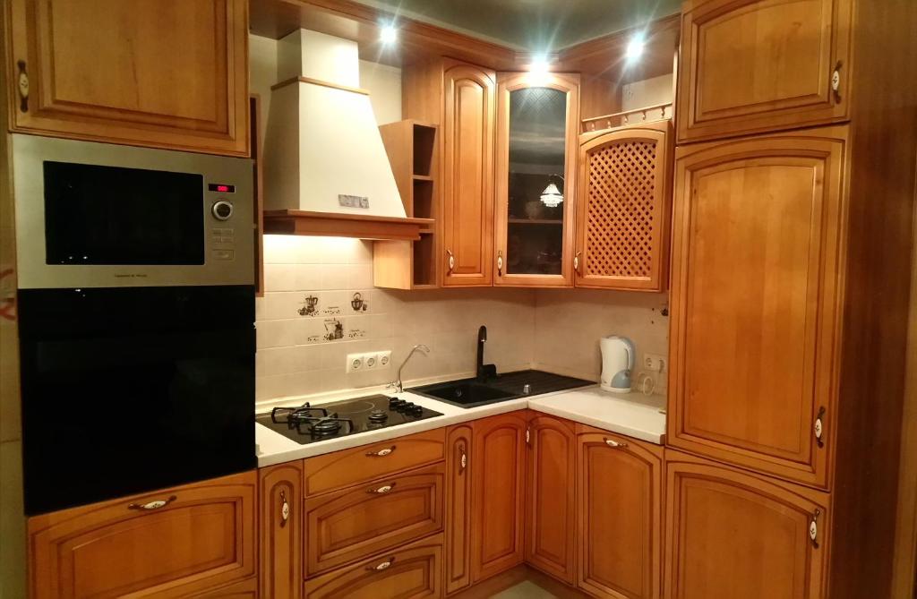 cocina con armarios de madera y nevera negra en Apartment on Tole Bi en Almaty