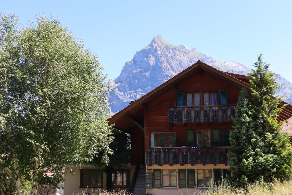 a house with a balcony with a mountain in the background at Harri's BnB in Kandersteg, Ferienwohnung in Kandersteg