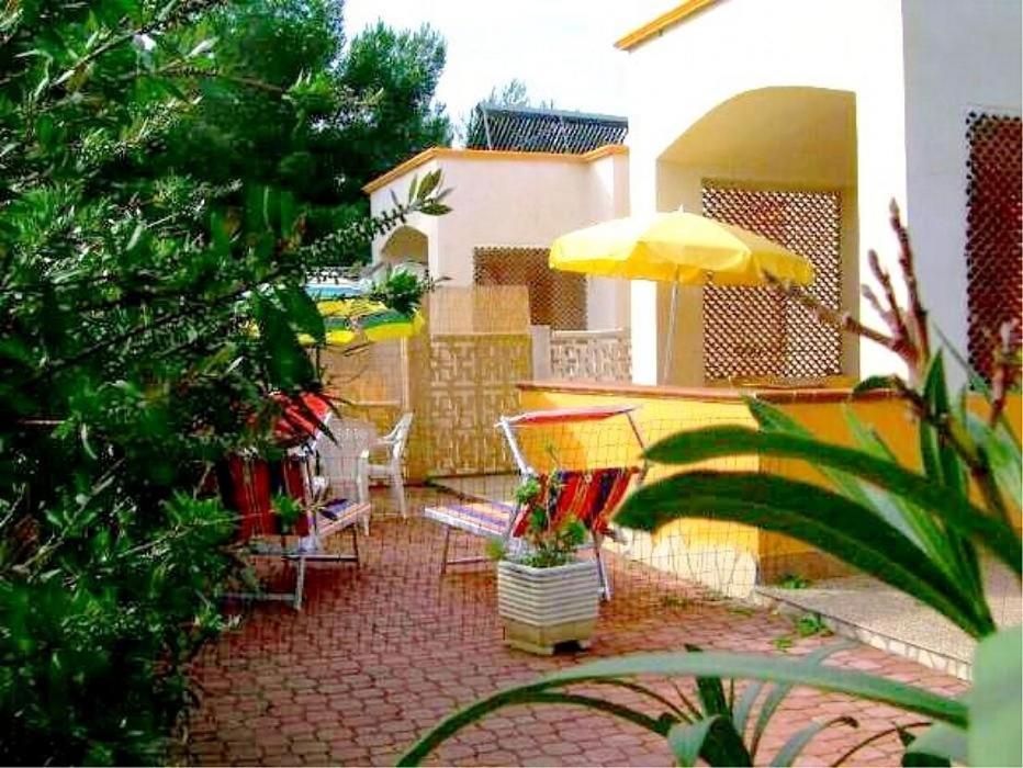 un patio con sillas y una sombrilla amarilla en Villa Carla, en Vieste