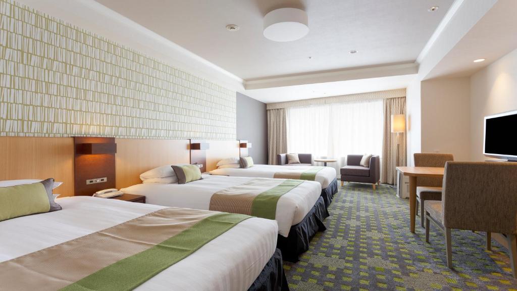 a hotel room with three beds and a television at Shibuya Excel Hotel Tokyu in Tokyo