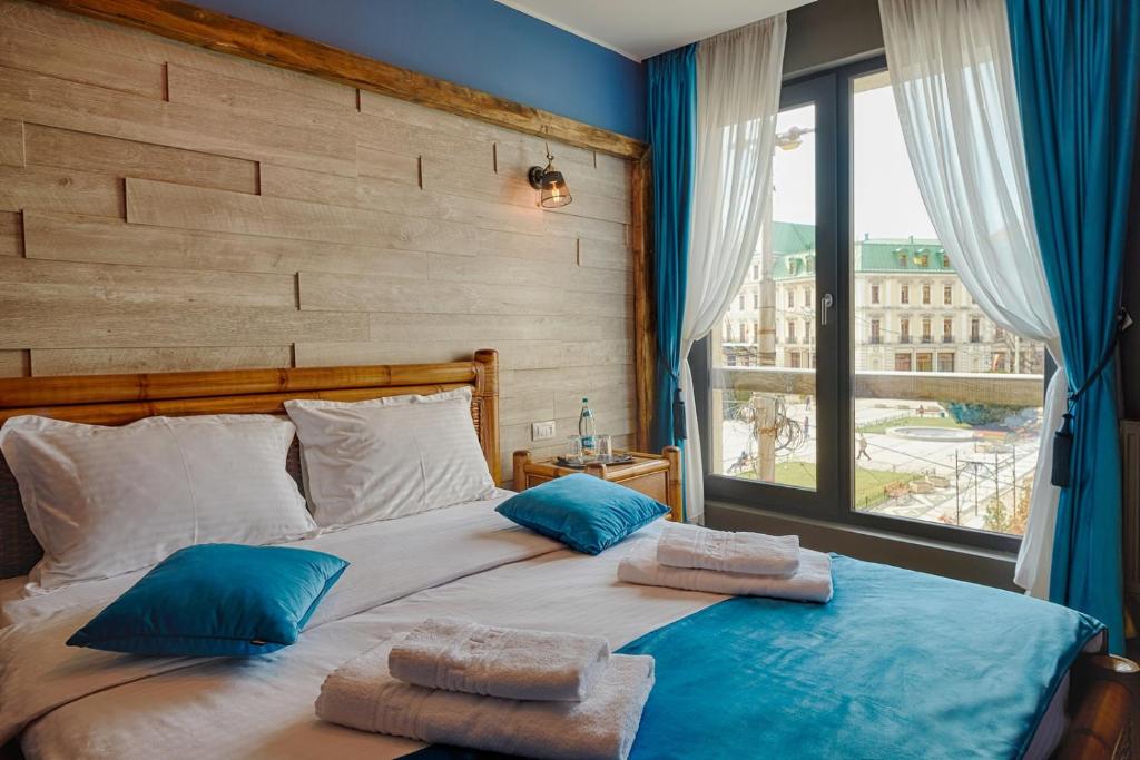una camera da letto con un grande letto con cuscini blu e una finestra di Piata Unirii Central Apartments a Iaşi