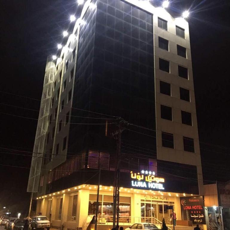 ein hohes Gebäude mit einem beleuchteten Schild davor in der Unterkunft luna hotel in Erbil