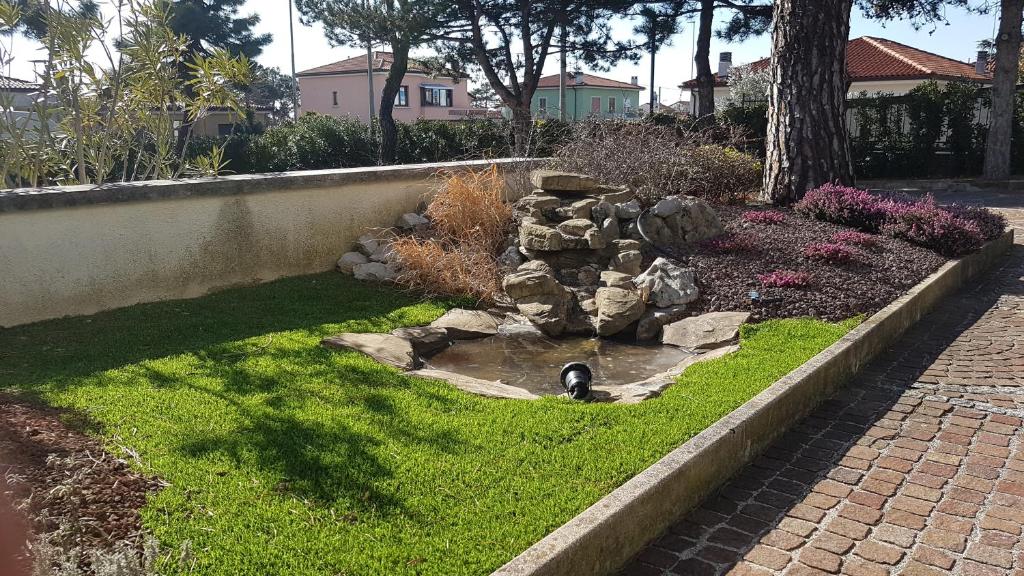 a garden with a small pond in the grass at Hotel Alla Dolina in Sistiana