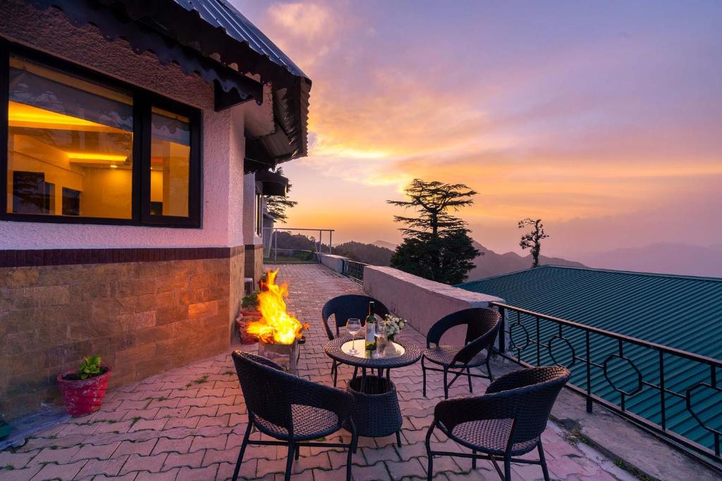 a patio with a table and chairs and a fire pit at StayVista at Cottage in the Clouds with Heater & Bonfire in Mussoorie