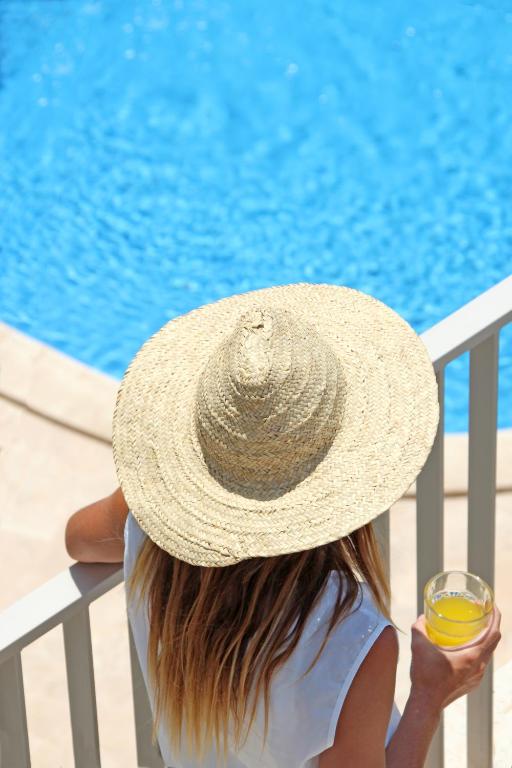 a woman wearing a straw hat with a glass of juice at Aparthotel Niu d´Aus in Portopetro