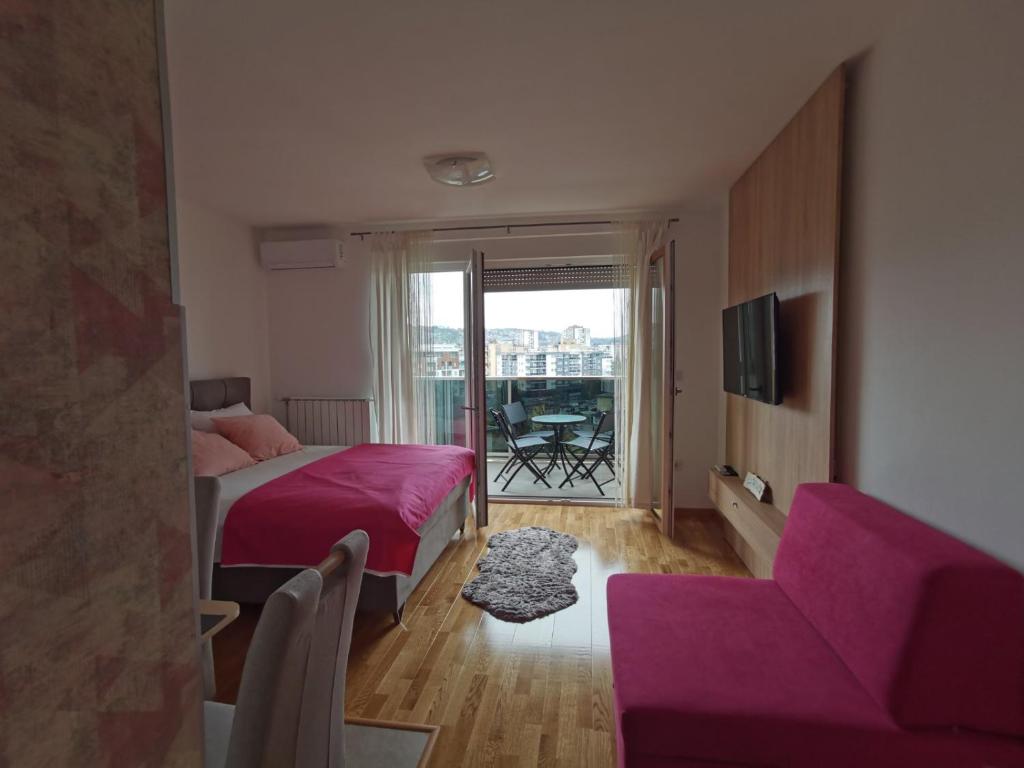 um quarto com uma cama rosa e um sofá em Apartman Krasula Doboj em Doboj