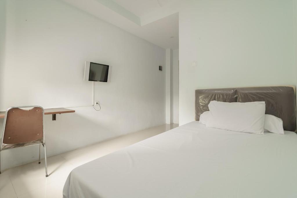 1 dormitorio blanco con 1 cama y 1 silla en KoolKost Syariah near Kampus Utama Universitas Budi Luhur, en Yakarta