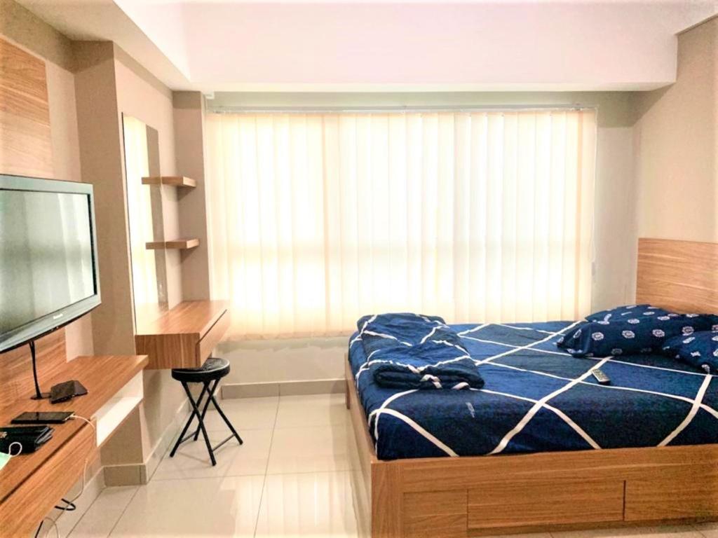 Springlake Apartment Summarecon by Veeroom في Rawabugel: غرفة نوم بسرير وتلفزيون بشاشة مسطحة