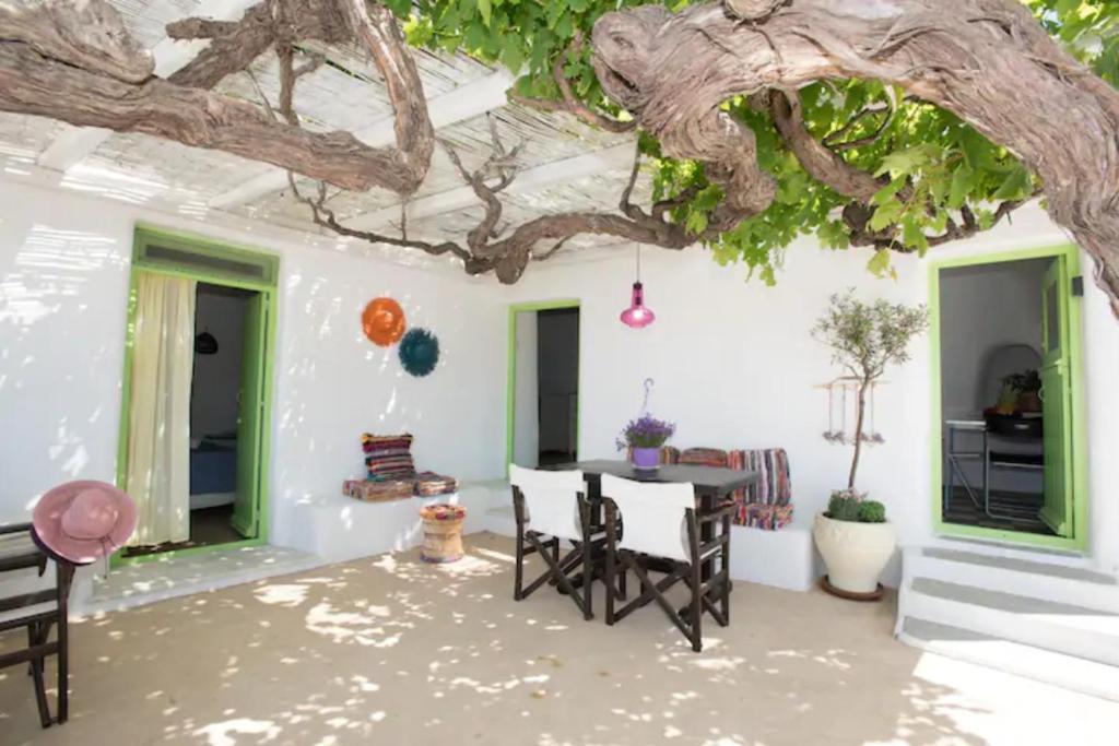 a patio with a table and chairs under a tree at Casa Annaise Mykonos - Cycladic House with Jacuzzi in Mikonos