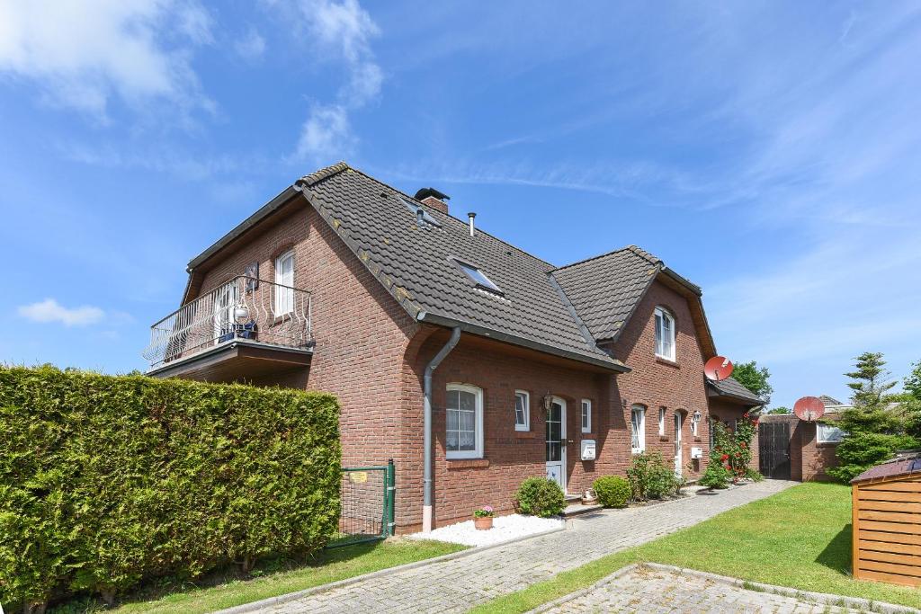 una casa de ladrillo con un seto delante en Ferienhaus Grodehus, en Dornumergrode