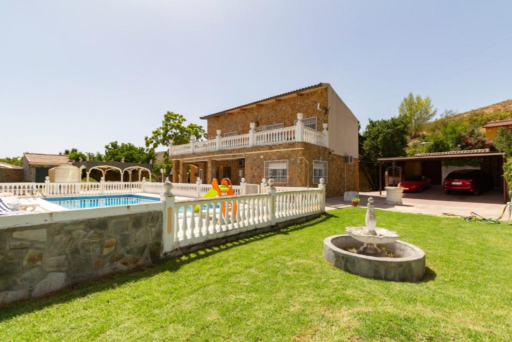 een huis met een hek en een tuin met een zwembad bij Finca bellas vistas in Padul