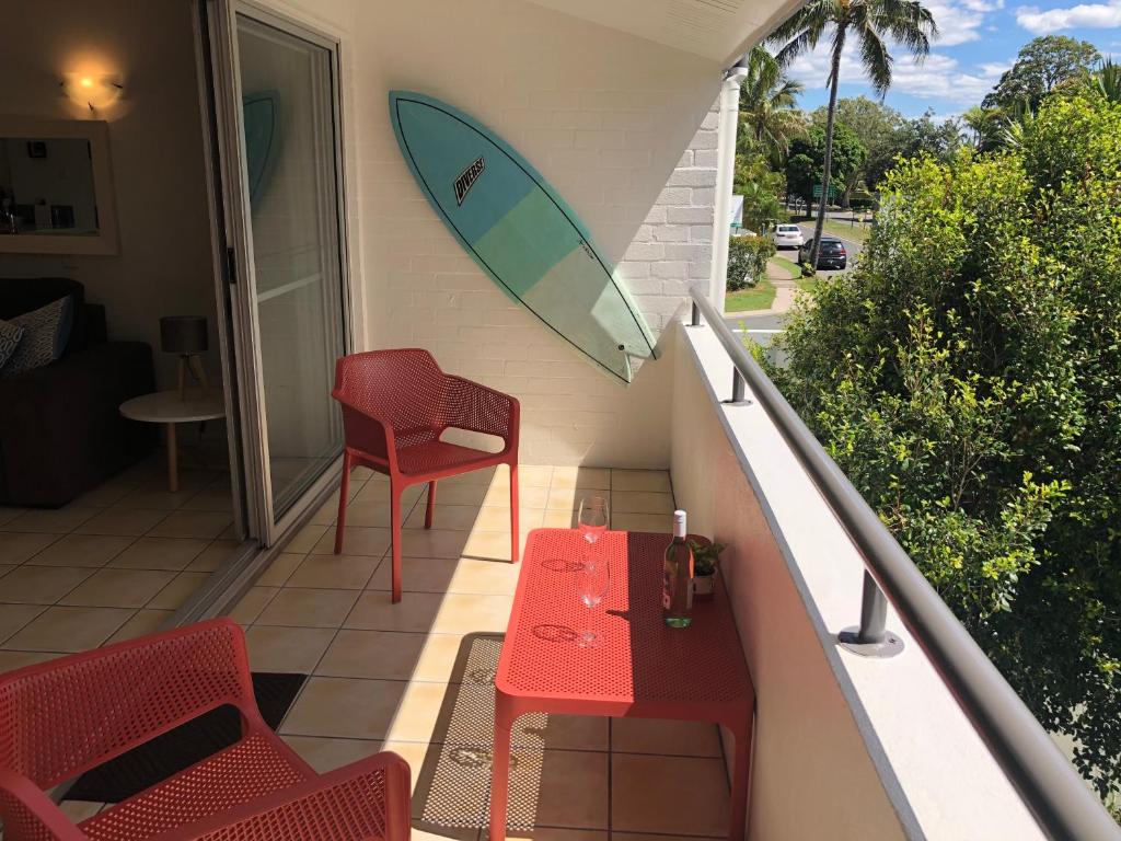 einen Balkon mit einem Tisch und einem Surfbrett darauf in der Unterkunft Noosa Retreat in Noosa Heads