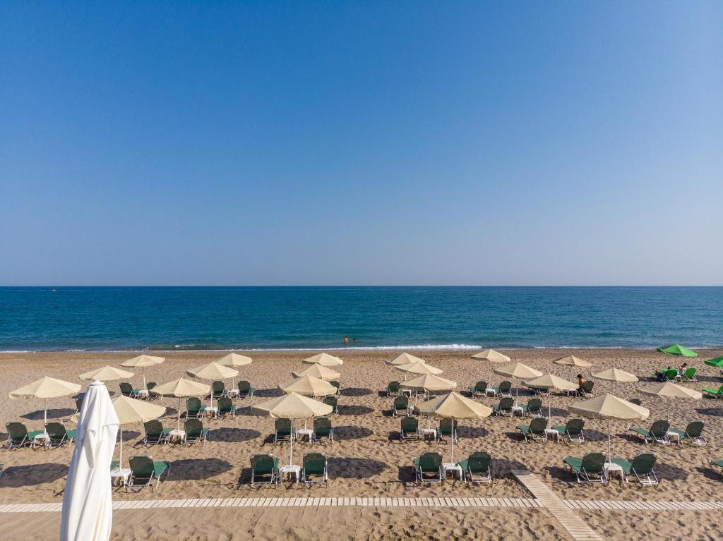 una playa con sombrillas y sillas y el océano en Princess Irini Sea Front ApartHotel, en Rethymno