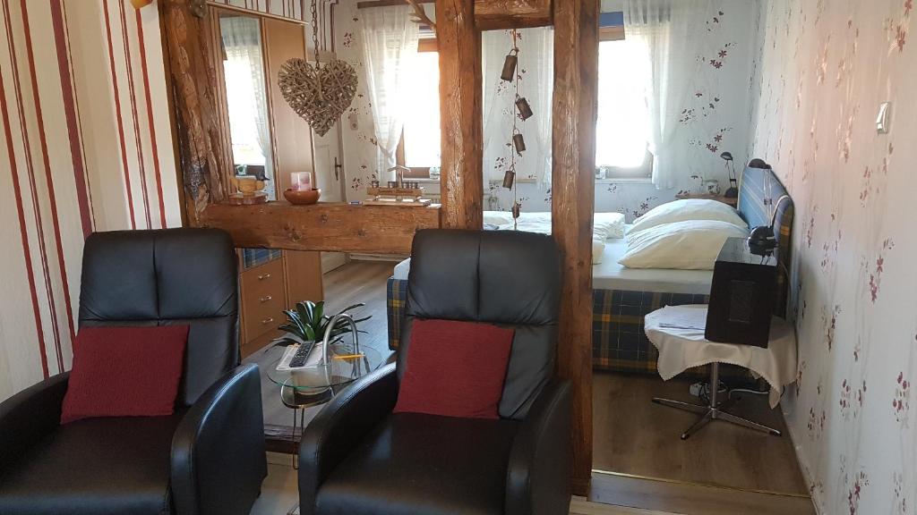 um quarto com 2 cadeiras, uma cama e um espelho em Haus Christa em Langelsheim