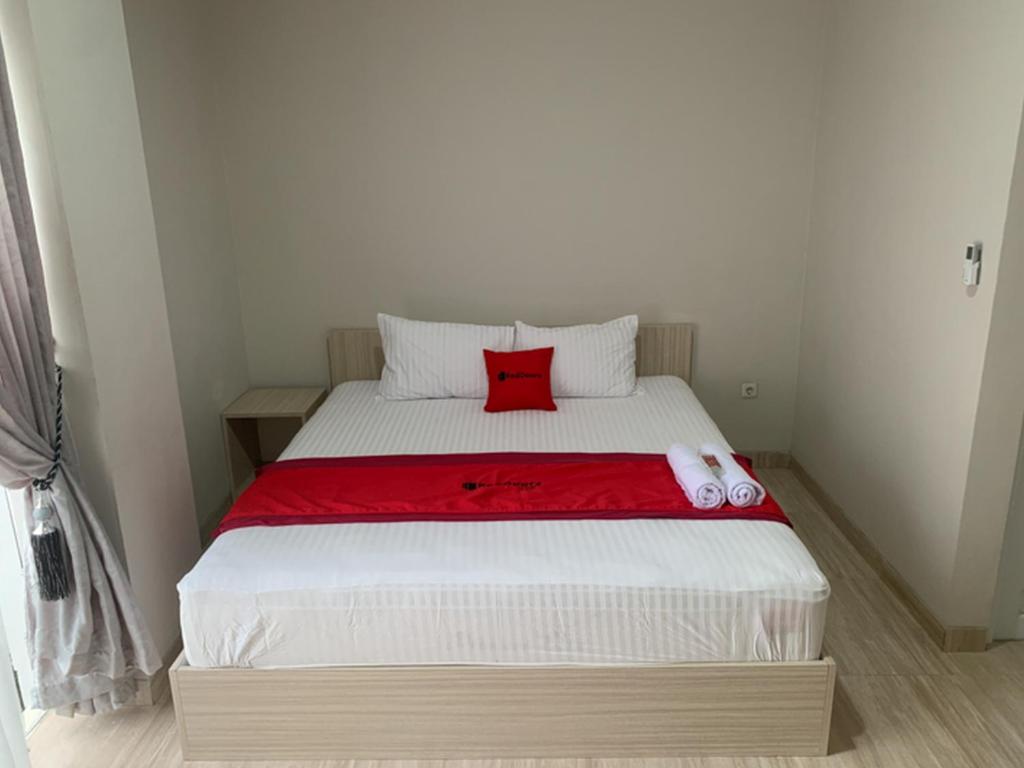 a bed with a red pillow on top of it at RedDoorz near Alun Alun Purbalingga in Purbolinggo