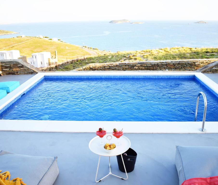 a table on a balcony with a view of the ocean at Antigoni Villas in Gavrio