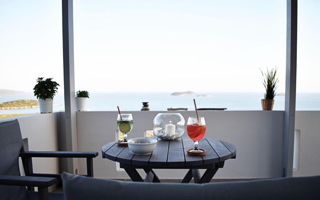 a table with two glasses of wine on a balcony at Antigoni Villas in Gavrio