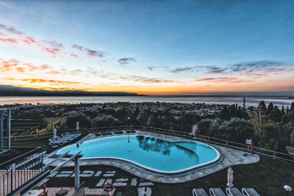 una piscina en la parte superior de un edificio con puesta de sol en La Chioma di Berenice Garda Residence, en Toscolano Maderno