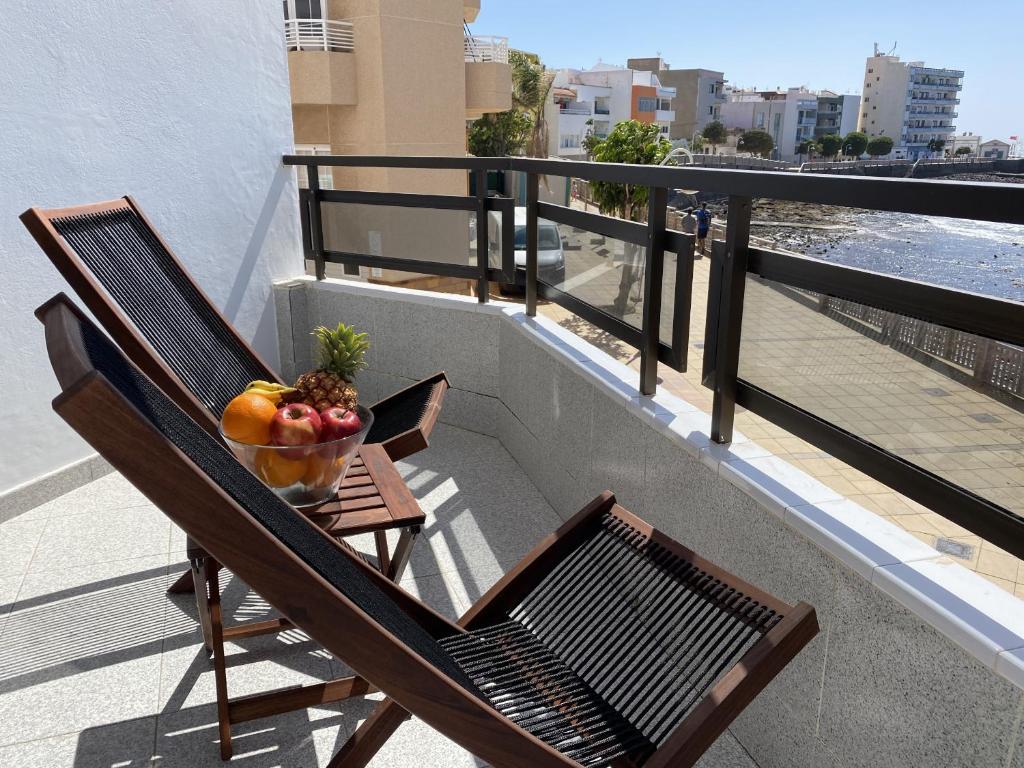 a bowl of fruit sitting on a chair on a balcony at Arinaga Colors, tu casa en la playa in Arinaga