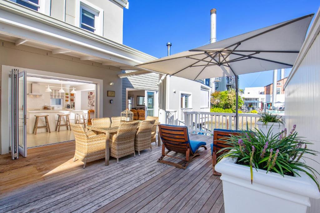 un patio con mesa, sillas y sombrilla en Thesen Island Holiday House, en Knysna