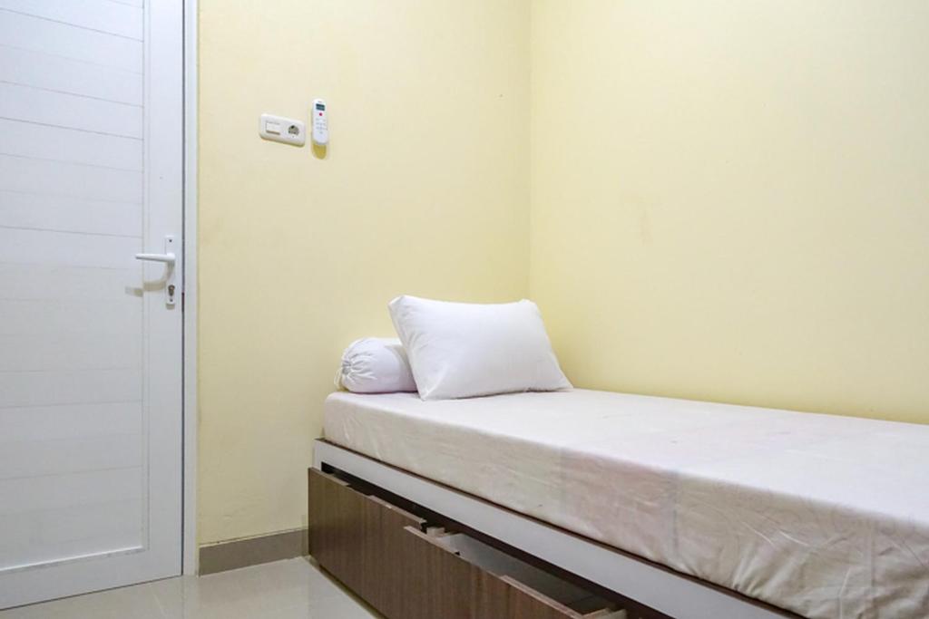 Habitación con cama con almohada blanca. en KoolKost Syariah near Sunter Mall - Minimum Stay 6 Nights, en Yakarta