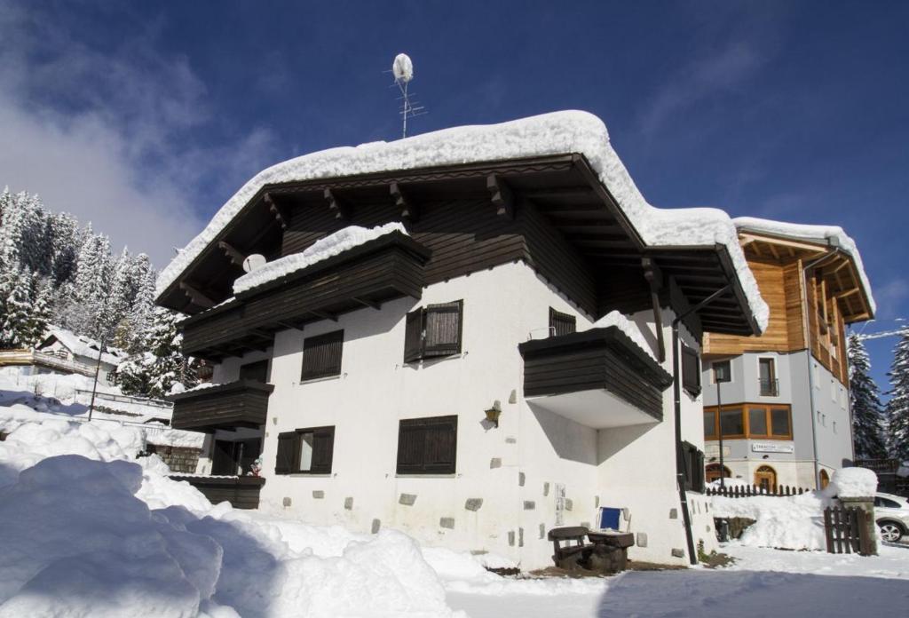 a house covered in snow with snow on the roof at Campiglio Trilocale Monte Spinale in Madonna di Campiglio