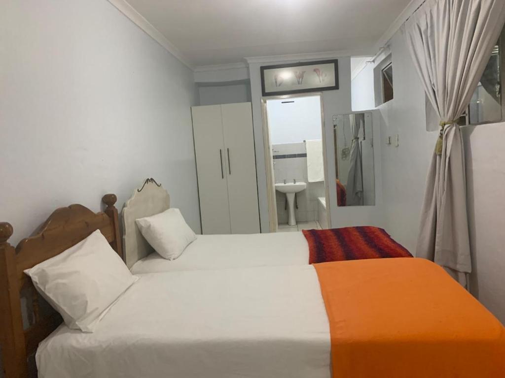 a small bedroom with two beds and a bathroom at Gold Reef Hideout in Johannesburg