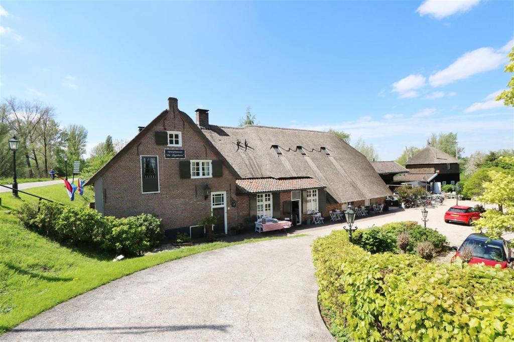 uma casa antiga com um telhado de palha e uma entrada em Herberg de Lingehoeve em Oosterwijk
