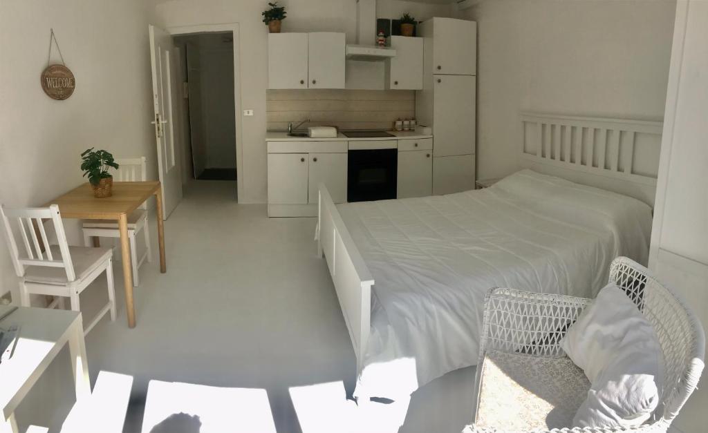 a white bedroom with a bed and two chairs at Magenta in Monopoli
