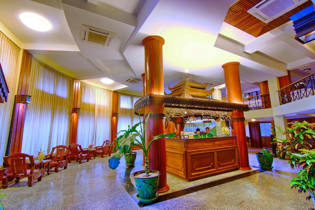 Shwe Ingyinn Hotel Mandalay في ماندالاي: لوبي كبير مع بار مع كراسي ومرآة