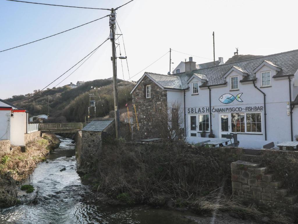 un pont sur une rivière devant un bâtiment dans l'établissement Tan Bryn 1, à Aberdaron