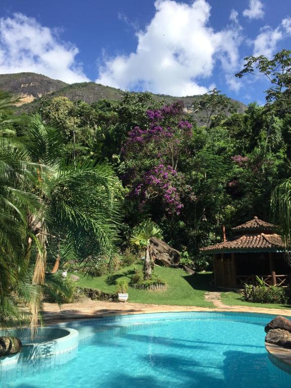 a swimming pool in front of a garden with trees at Guest House Tânia Alves in Pratinha